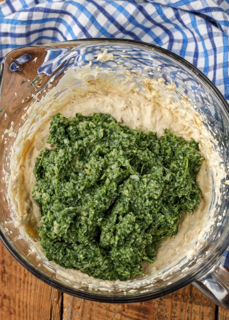 pureed spinach added to creamy dip in bowl