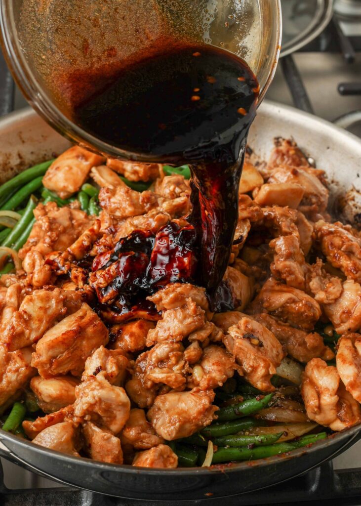 stir fry sauce poured into skillet over chicken