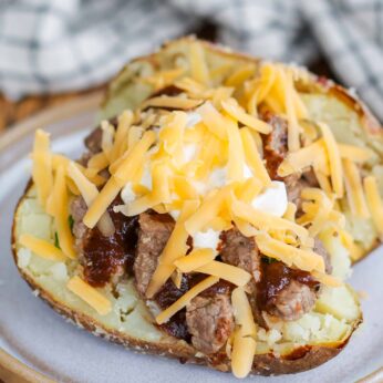shredded cheese and the other toppings have been placed atop a baked potato in this vertically aligned image.