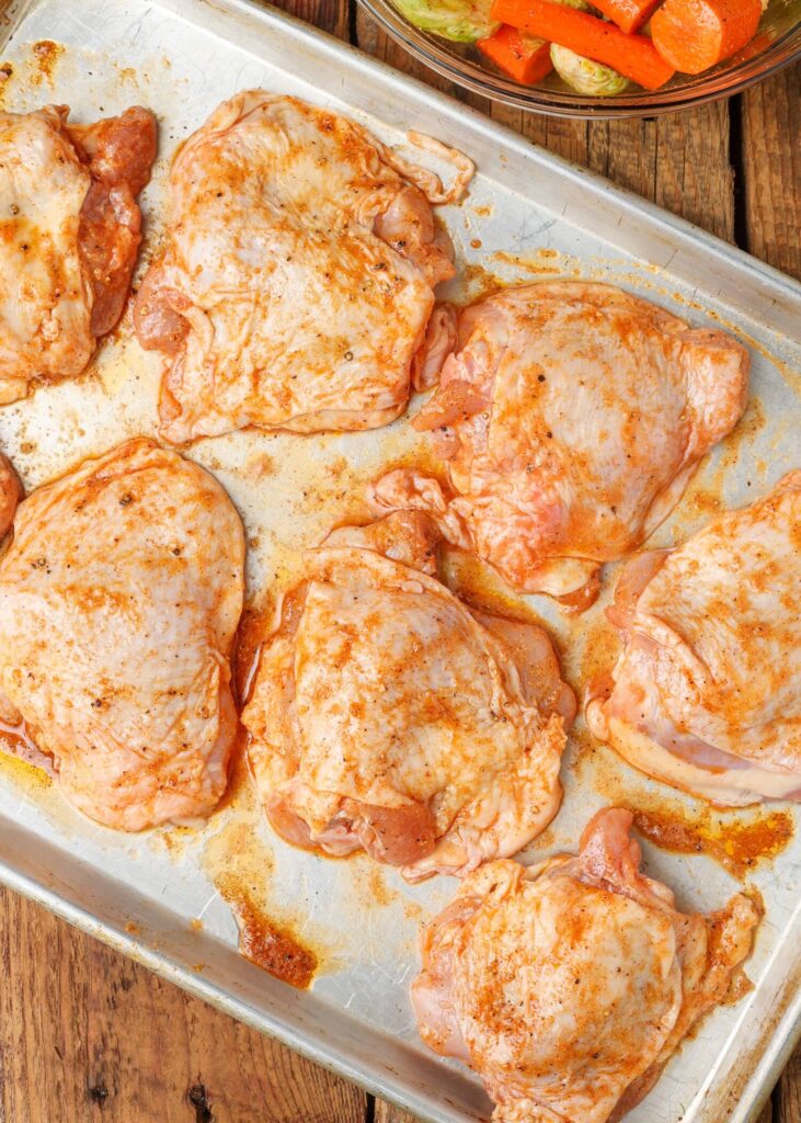 raw chicken with marinade on sheet pan