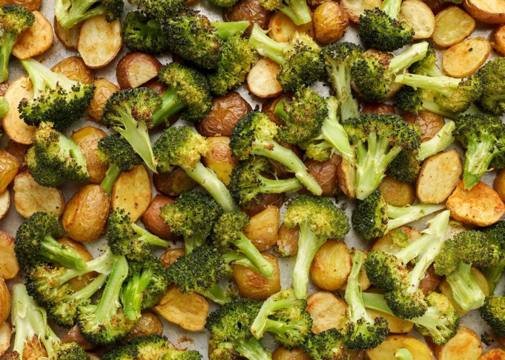 metal sheet pan heaped with broccoli and potatoes, fresh from the oven.