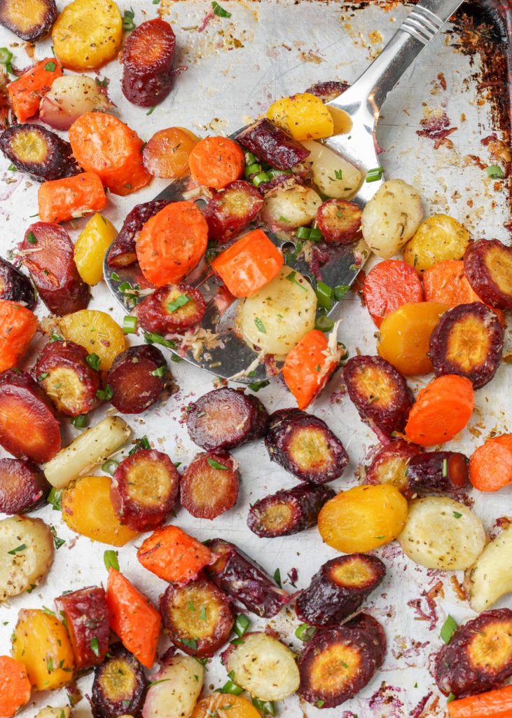 roasted rainbow carrots with garlic and Parmesan on baking tray with spatula