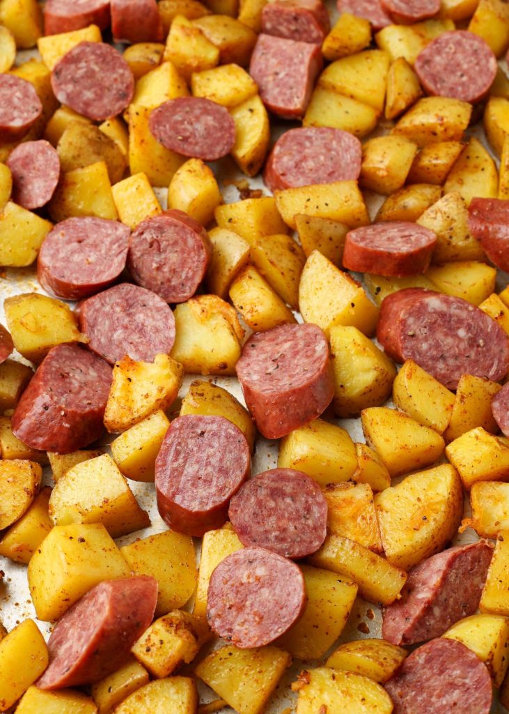 sliced sausage and potatoes on pan ready to bake