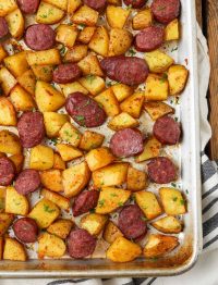 sheet pan with potatoes and sausage on blue towel