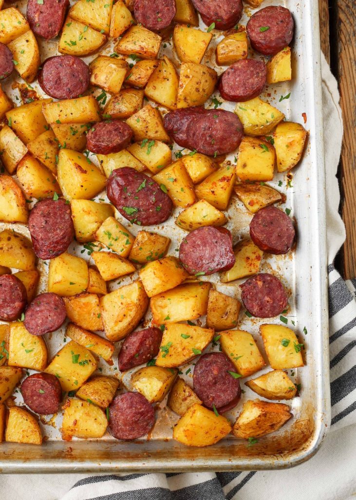 sheet pan with potatoes and sausage on blue towel