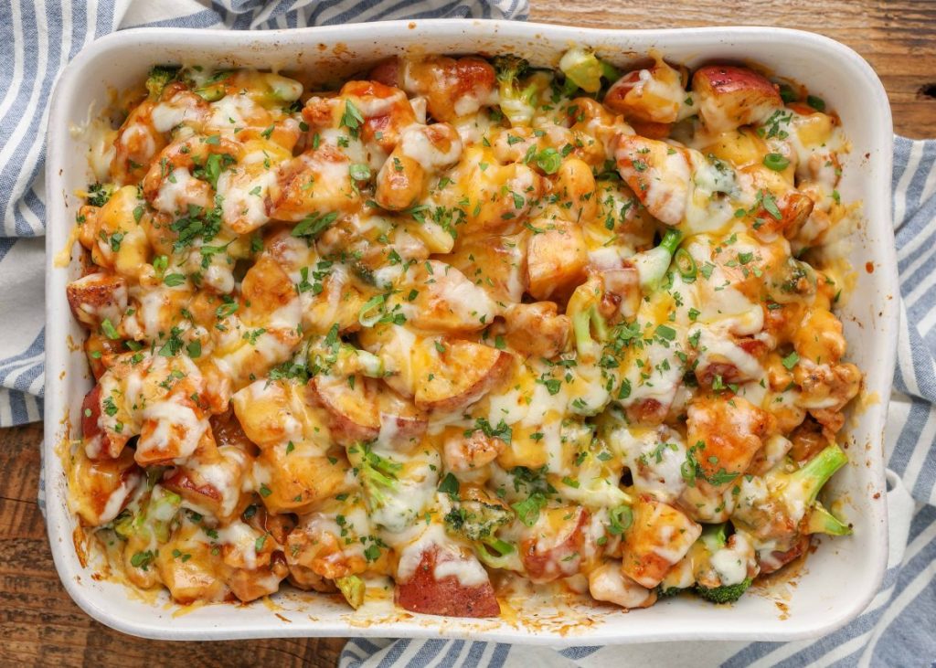 chicken, potatoes, and vegetables in baking dish with cheese