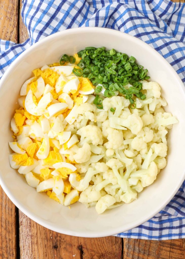 cauliflower, hard boiled eggs, and green onions in mixing bowl