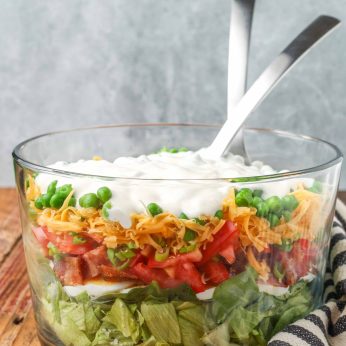 salad in clear bowl with dressing on top with tongs in bowl