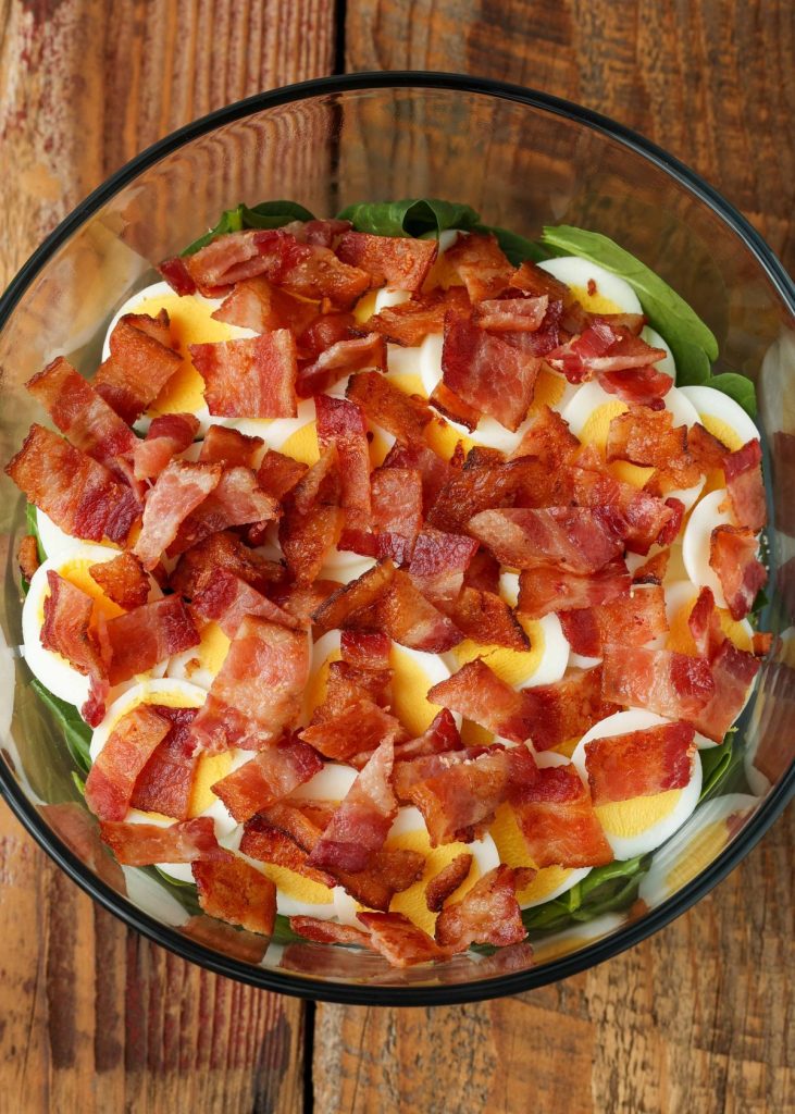 bacon and eggs on salad greens in large bowl