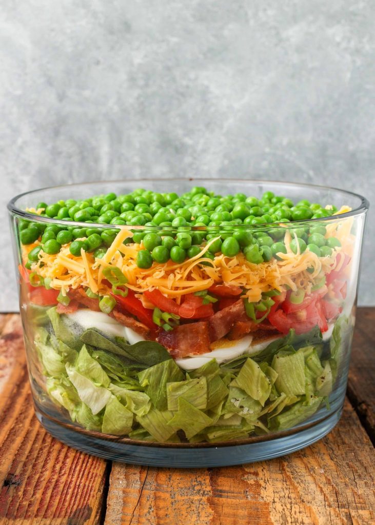 salad with 7 layers in clear bowl on wooden table