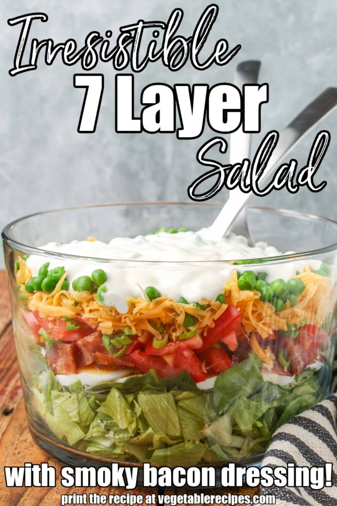 7 layer salad with smoky bacon dressing in bowl with silver utensils