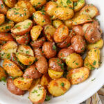 A top down image of a mountain of Garlic Herb Roasted Potatoes in a white bowl.
