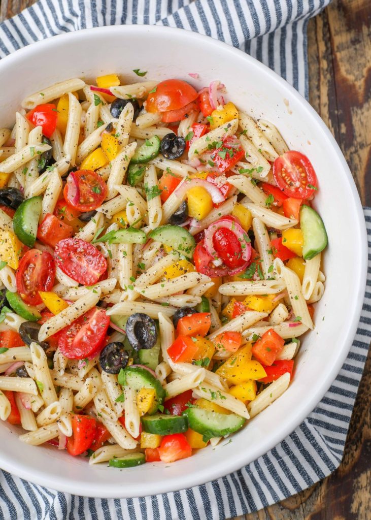 vegetable filled pasta salad in serving bowl with striped towel