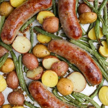 Oven Roasted Brats with Potatoes and Green Beans on metal pan