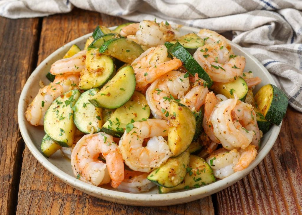 shrimp and zucchini on pottery plate on wooden table