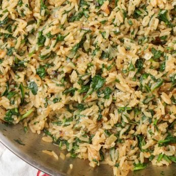 creamy rice with spinach in skillet with tea towel