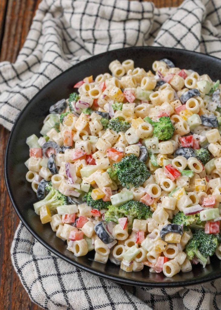 creamy pasta with lots of vegetables in black serving bowl 