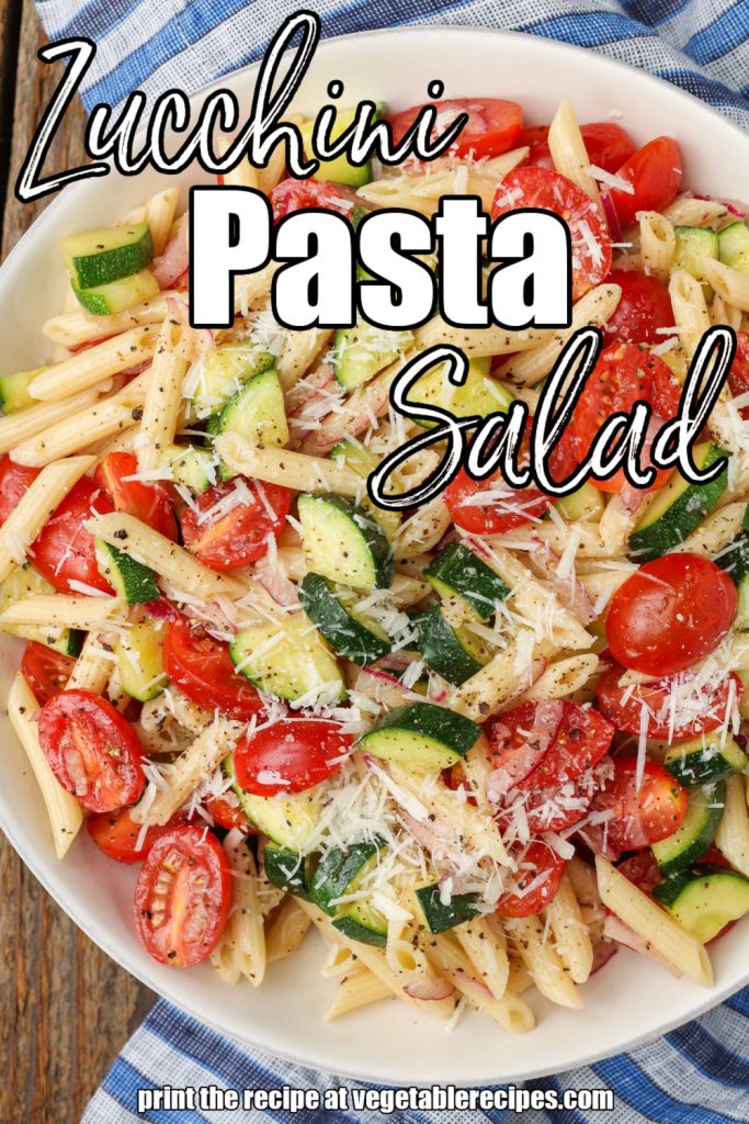 pasta salad with zucchini in white bowl with blue napkin