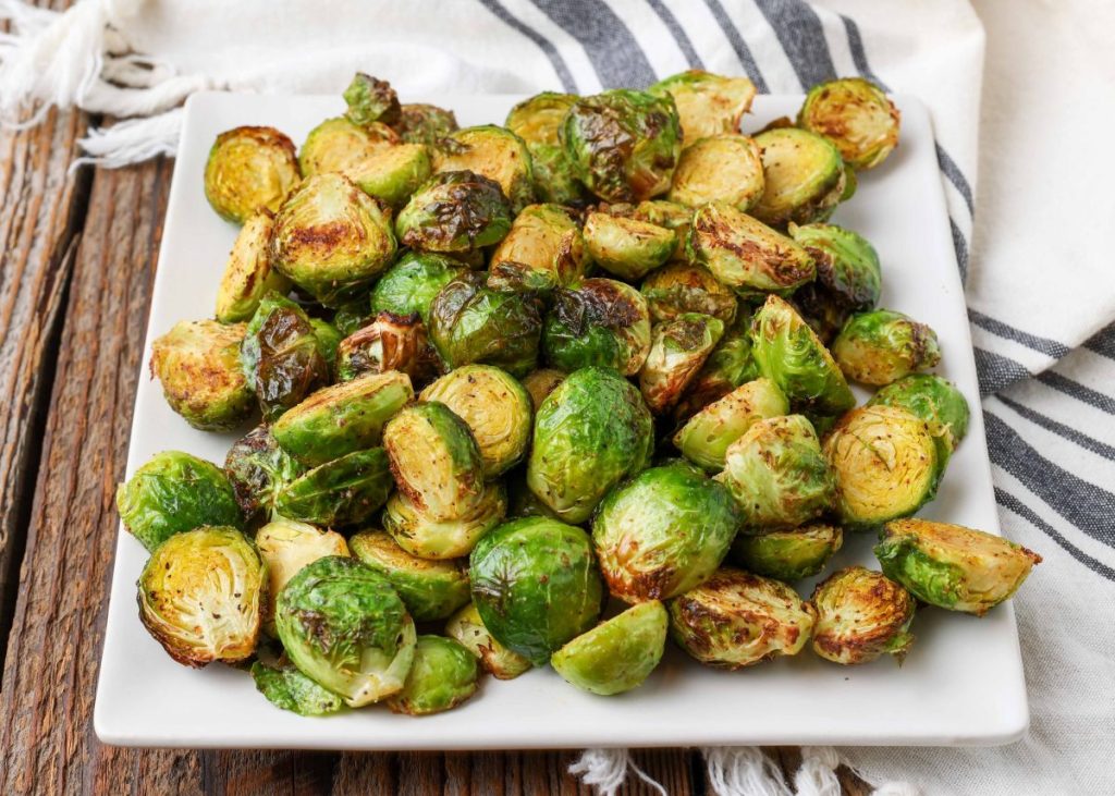 Cajun Brussels sprouts on square plate with blue towel