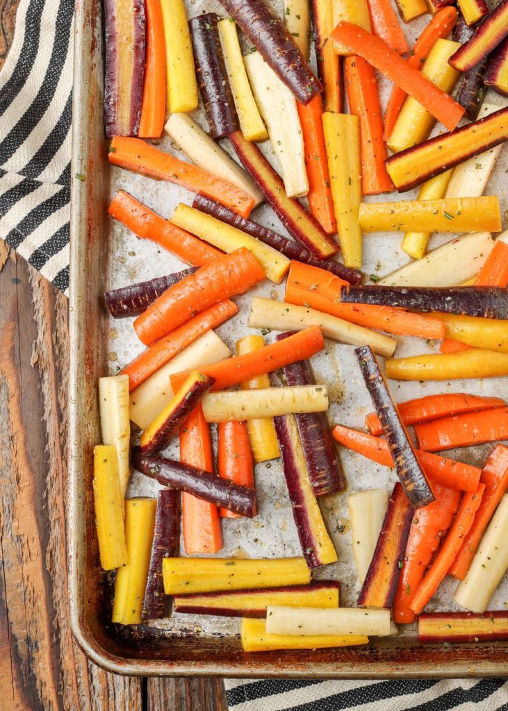 rainbow carrots on sheet pan coated with with maple syrup, honey, and herbs 