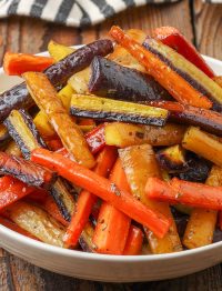 caramelized roasted rainbow carrots in white dish with black and white napkin