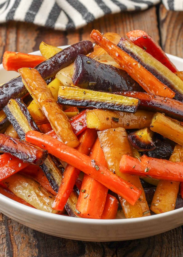 caramelized roasted rainbow carrots in white dish with black and white napkin