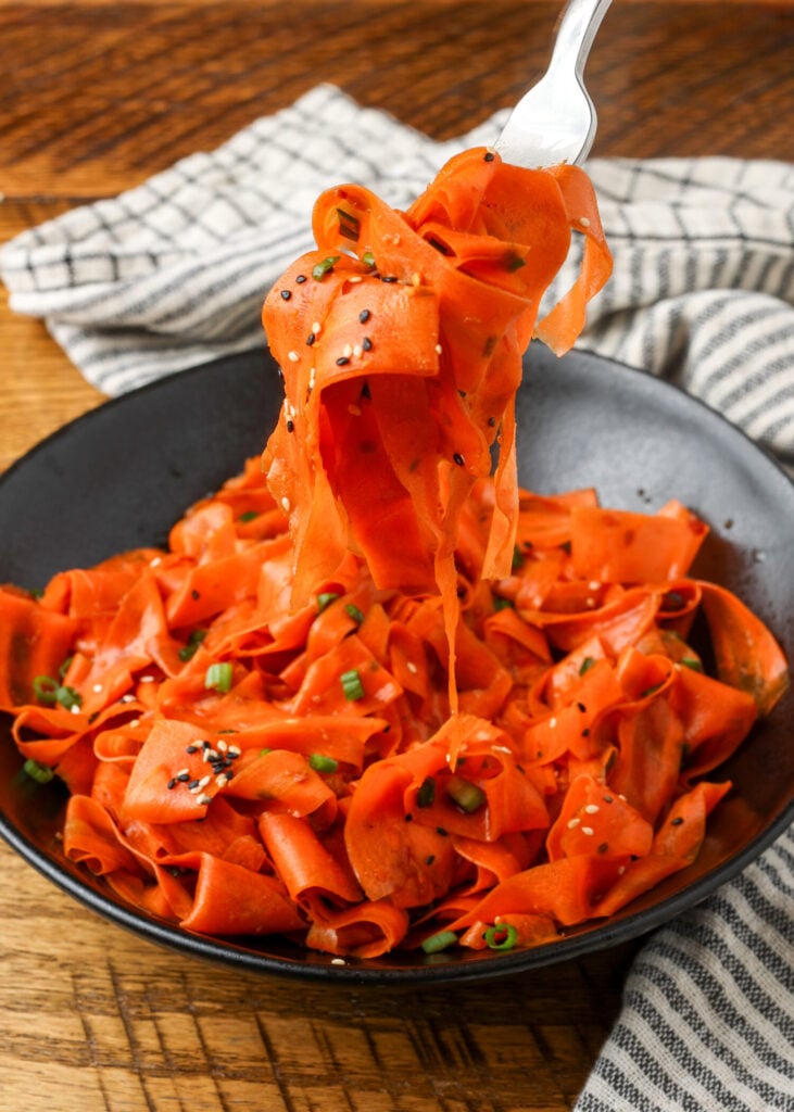 A fork shows the long thin ribbons of carrot in this salad.