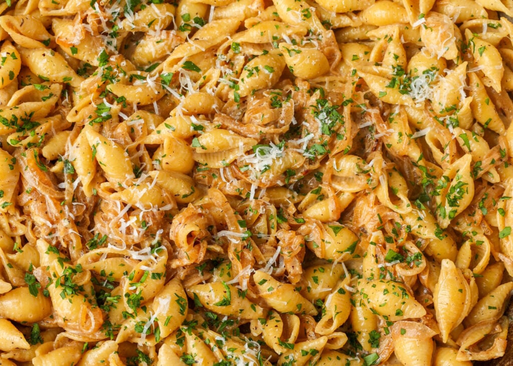 A close up showing the herbs and fresh parmesan grated over the Caramelized Onion Pasta.
