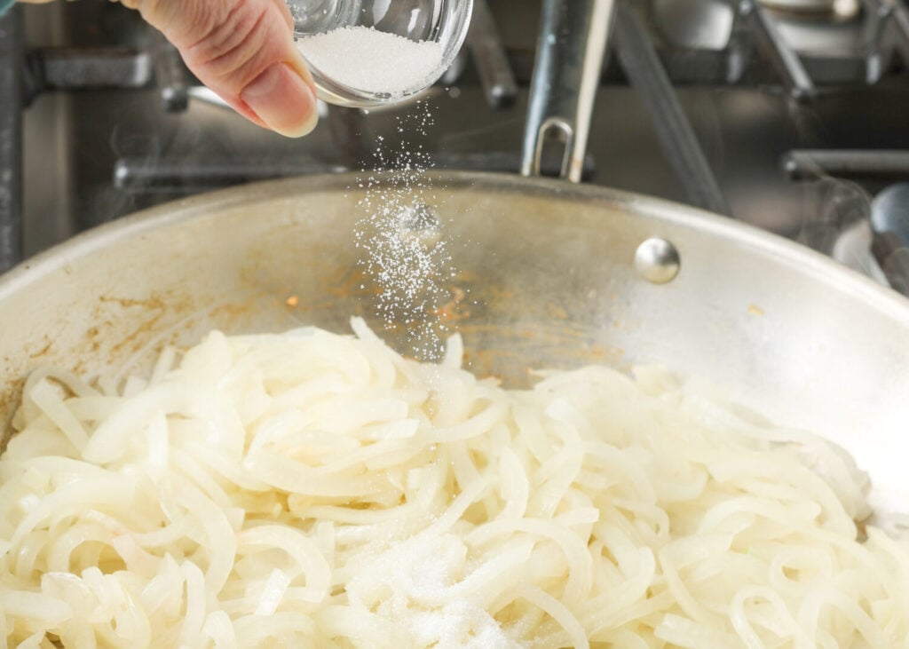 An action shot, showing the salt being added to the fresh slices of yellow onion.