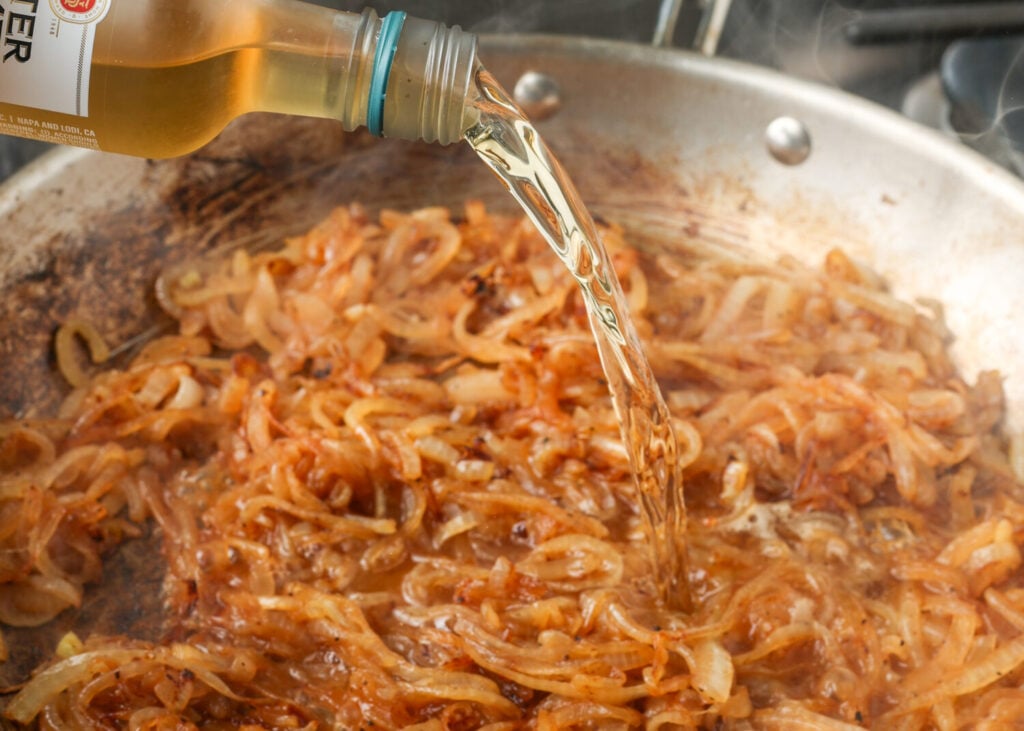 Adding the white wine to deglaze the pan full of caramelized onions.