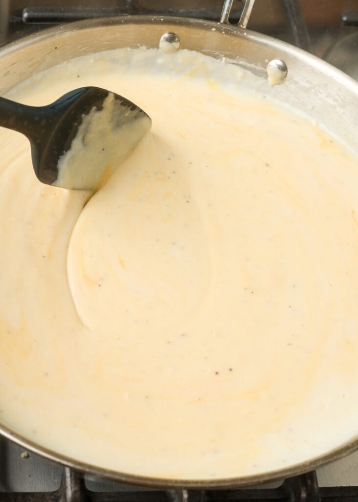 stirring cream sauce in skillet