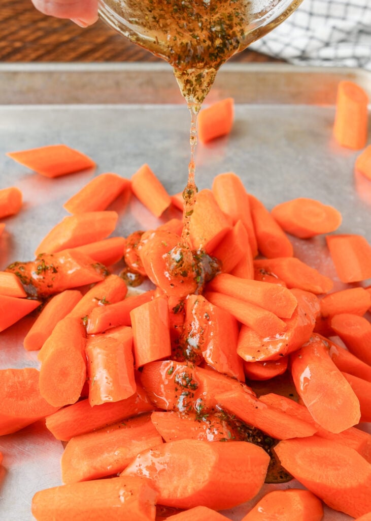 drizzling the glaze over carrots on sheet pan