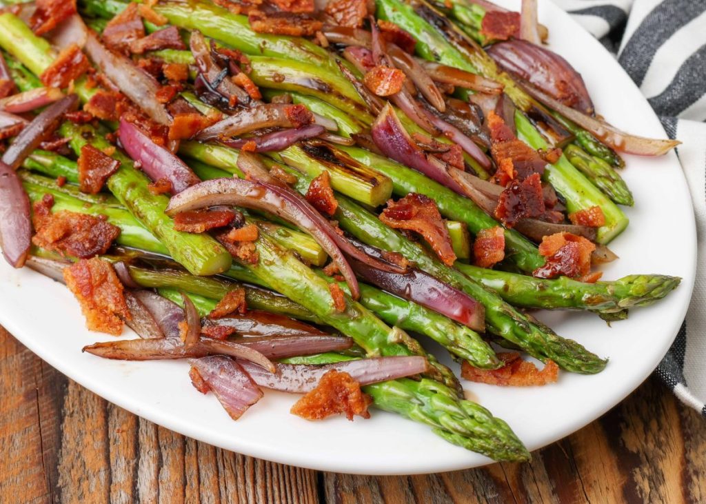 asparagus with bacon and onion on oval plate with napkin