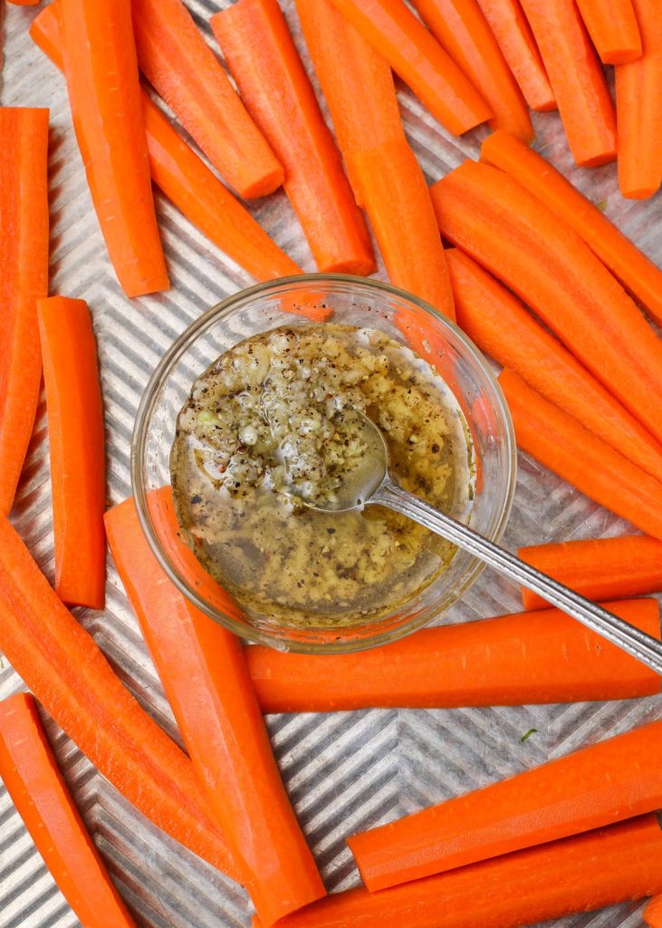 Carrots with garlic and oil on baking sheet
