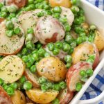 creamed peas and tiny potatoes in white dish with blue plaid napkin