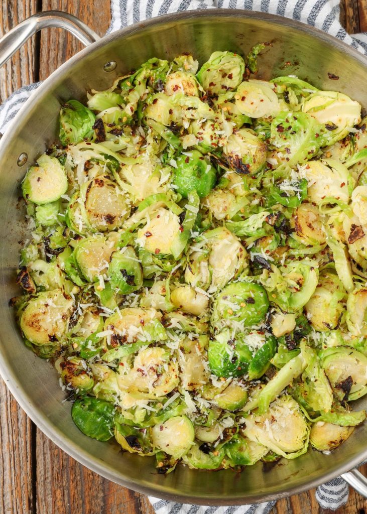 Lemon and garlic sauteed Brussels in stainless skillet with striped towel
