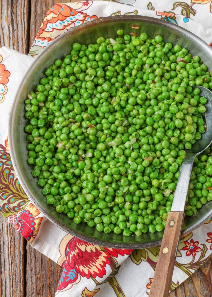 peas with garlic and onion in large stainless skillet with wooden spoon