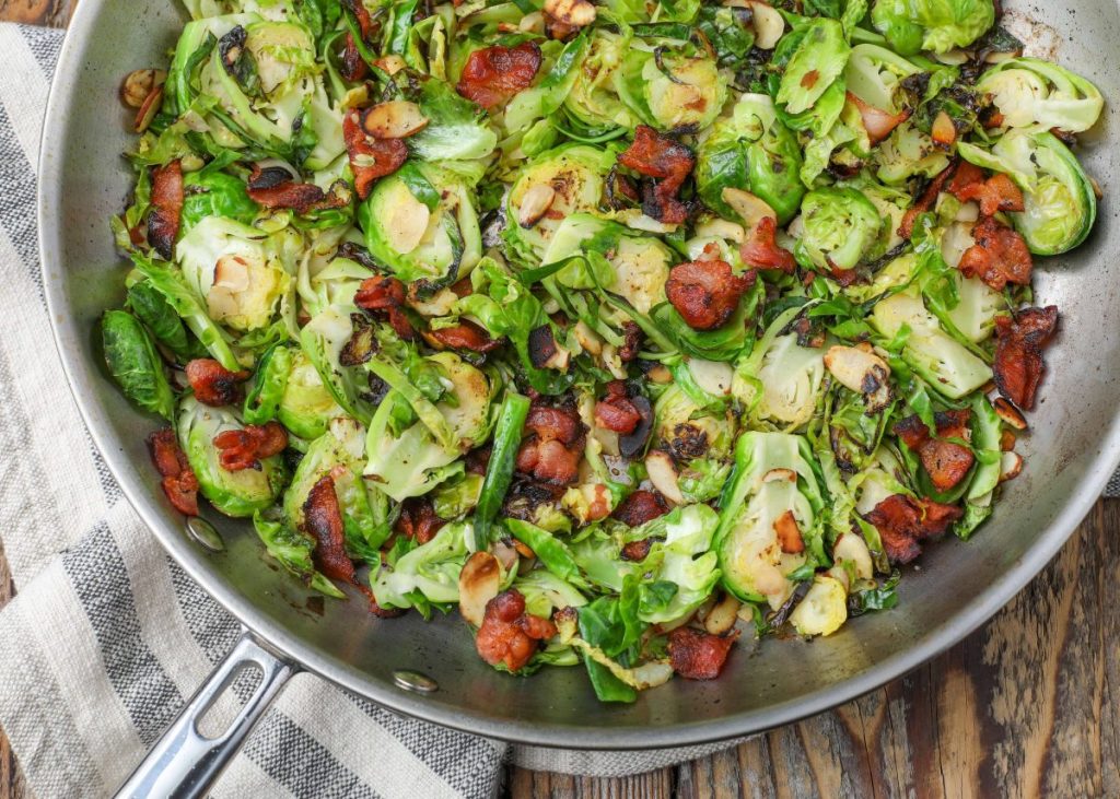Brussels with bacon and almonds in skillet with tea towel