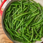 finished green beans in red enamel skillet on wooden table