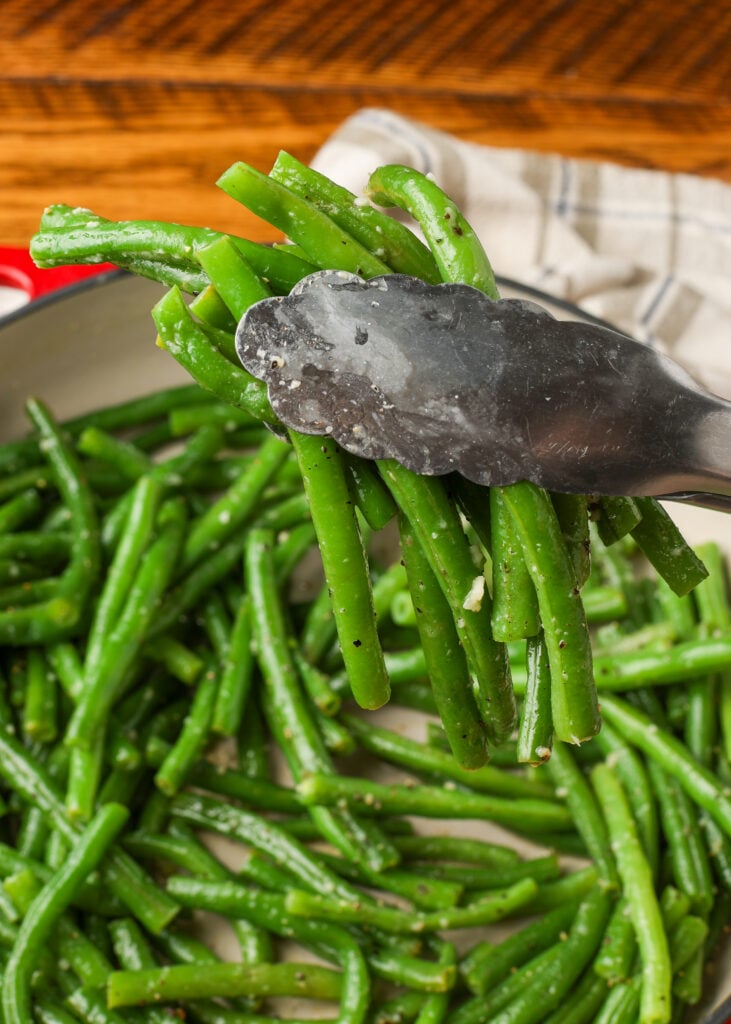 vertical shot of tongs holding green beans