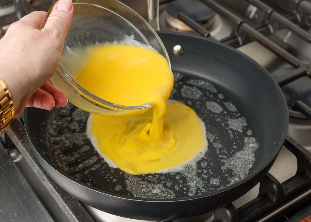 pouring eggs into skillet with butter