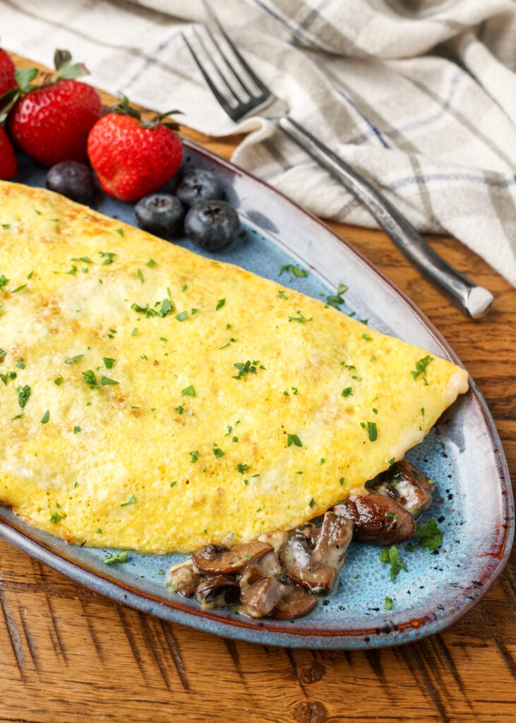 omelet filled with mushrooms on blue pottery plate