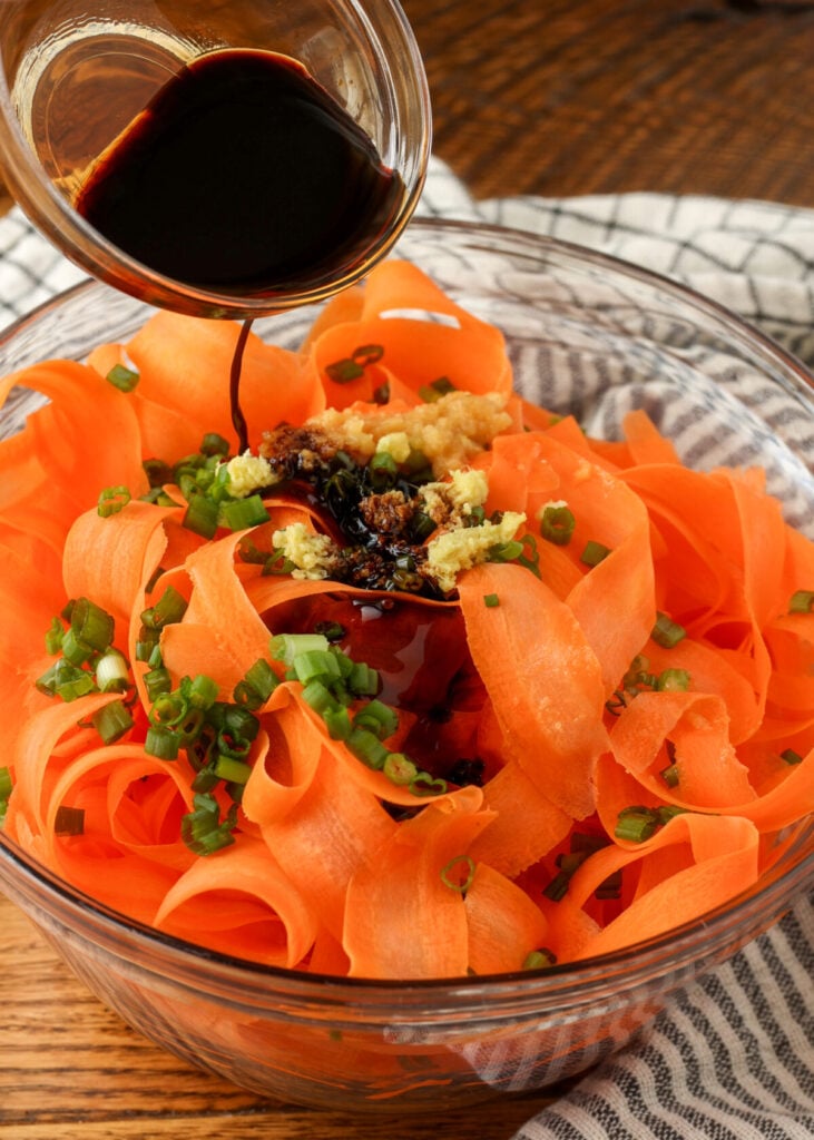 adding soy sauce to carrot salad