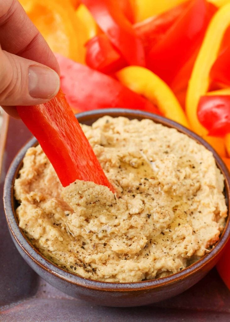 bell pepper being dipped into hummus